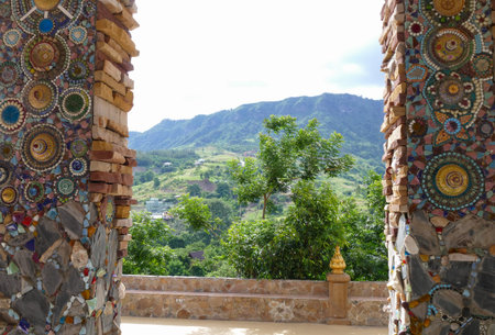 the art design of the colorful broken tile and stone decorating on temple pole with mountain view