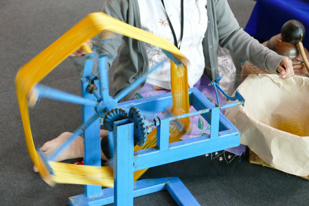 Chiang Mai, Thailand - August 28, 2015: The girl is demonstrating how to spin silk floss yarn with traditional silk yarn wheel at Chiang Mai International Exhibition and Convention Centre.のeditorial素材