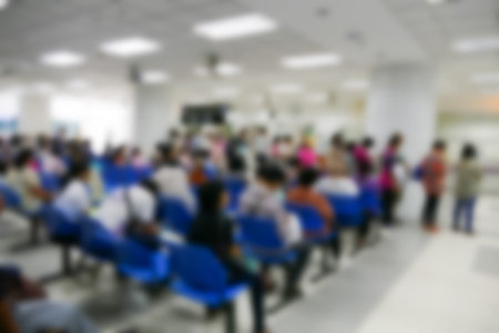 blurry defocused image of people standing and sitting in public hospital