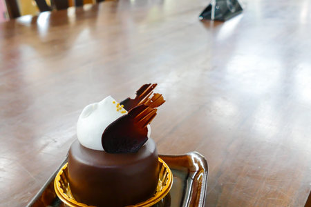 small piece of round chocolate cake with cream on top
