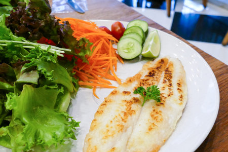 grilled fish fillet with sasame sauce and vegetable salad (tomato, carrot, cucumber, lime, red...