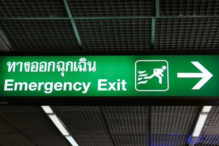 emergency exit sign in english and thai language in the buildingの写真素材