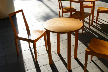 wooden chair and table at the patio of cafe with sunlight and shadow