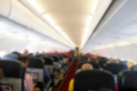 blurry defocused image of people sitting in economy class seat in the airplane