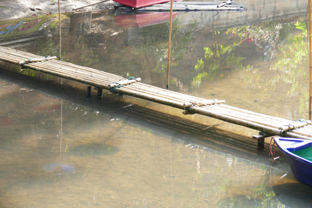 blue boat and bamboo footbridge across the creekの写真素材