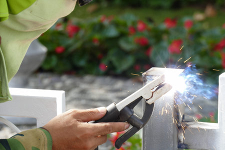 The worker welding the iron steel pole