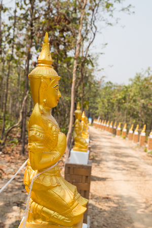 golden asian angel statue beside the walkway in forestの写真素材