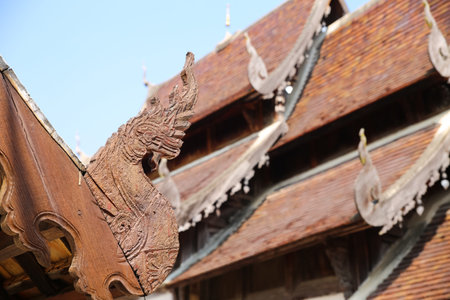 the design of wooden naga sculpture on ancient buddhism temple roof