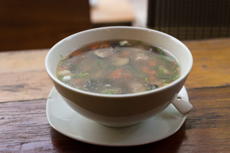 rice congee mixed with pork, shiitake mushroom and carrot in a bowl on wooden table