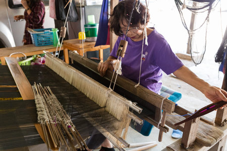 Lamphun, Thailand - February 17, 2016: Woman using traditional loom to weave thailand textile at...