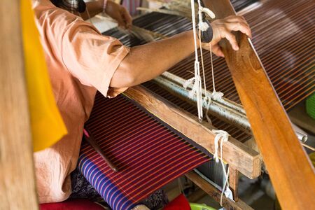 Woman using traditional loom to weave thailand textileの写真素材