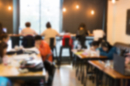 blurry defocused image of people reading and working in cafeの写真素材