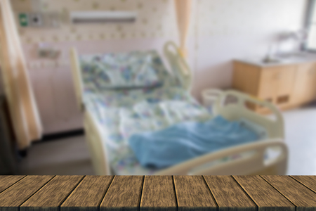 empty bed for patient in private room (blur background with wood table top for display or montage your product)の写真素材