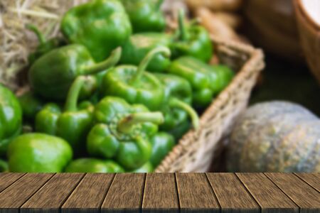 stack of green sweet bell pepper in the basket (blur background with wood table top for display or montage your product)の写真素材