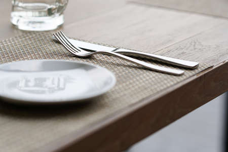 empty glass mug, cutlery and white dish on wooden tableの写真素材