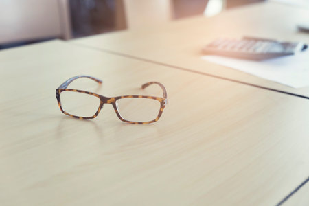 eyeglasses calculator and business document on wooden table, vintage tone