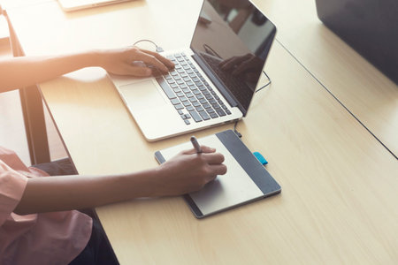 man' hand holding pen working on digital tablet and computer notebook for graphic design work,...