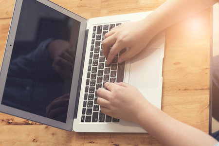woman's hand typing with laptop computer notebook for working concept, selective focus and vintage toneの写真素材