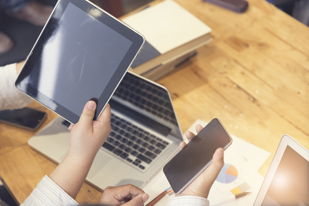 man's hand working with mobile phone, tablet, business document and laptop computer notebook for working concept, selective focus and vintage toneの写真素材