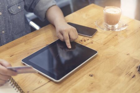 woman's hand holding credit card with tablet for shopping online concept, selective focus and vintage toneの写真素材