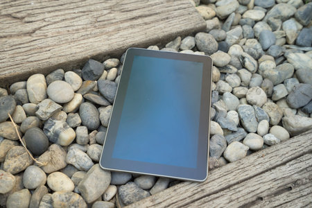 digital tablet device on stone and wooden walkway in garden
