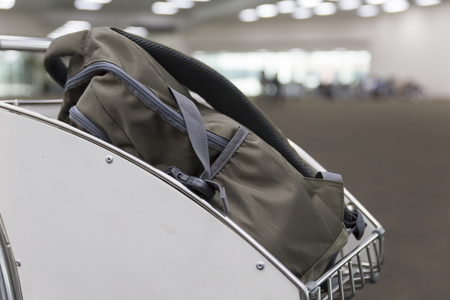 brown rucksack on trolley cart in airport terminal building for travel conceptの写真素材