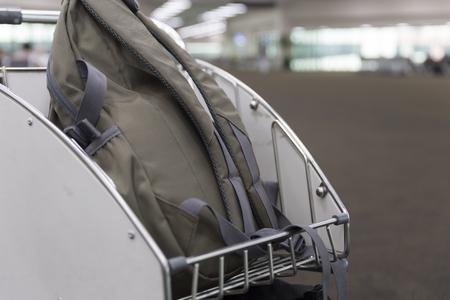 brown rucksack on trolley cart in airport terminal building for travel conceptの写真素材