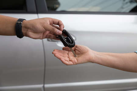 people's hand give and get car key with silver car backgroundの写真素材