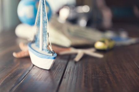 map, globe, ship and car figurine, starfish, banknote, camera on wooden table for use as trip...