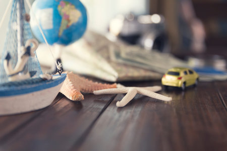 map, globe, ship and car figurine, starfish, banknote, camera on wooden table for use as trip...