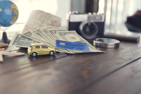 car figurine, compass, credit card, banknote money, globe, camera, map, starfish on wooden table for use as traveling concept (vintage tone and selected focus)の写真素材