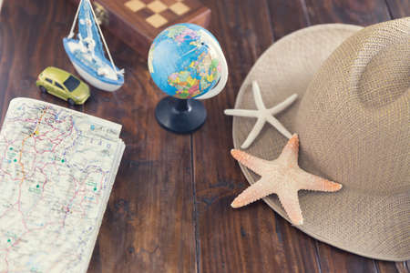 globe, hat, map, car ship and starfish figurine on wooden table for use as traveling concept (vintage tone and selected focus)の写真素材