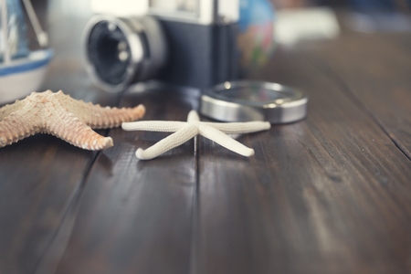 camera, compass, globe,ship and starfish figurine on wooden table for use as traveling concept (vintage tone and selected focus)の写真素材