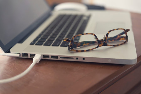 laptop computer, mouse and eyeglasses on wooden table for use as working concept (vintage tone and selected focus)の写真素材