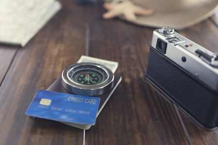 passport, camera, compass, credit card, banknote, map, hat on wooden table for use as traveling concept (vintage tone and selected focus)の写真素材