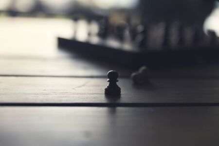 silhouette of pawn and chess game on wooden table, vintage tone and selected focusの写真素材