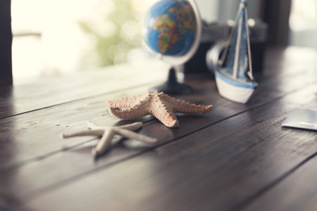 globe, credit card, camera, ship and starfish figurine on wooden table for use as traveling concept (vintage tone and selected focus)の写真素材
