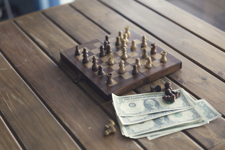 pawn of chess game and money banknote on wooden table for use in business competition concept, vintage tone and selected focusの写真素材