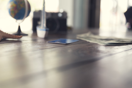 credit card, banknote money, globe, camera, ship and starfish figurine on wooden table for use as traveling concept (vintage tone and selected focus)の写真素材