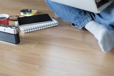 man sitting on floor with laptop computer, coffee cup and eyeglasses