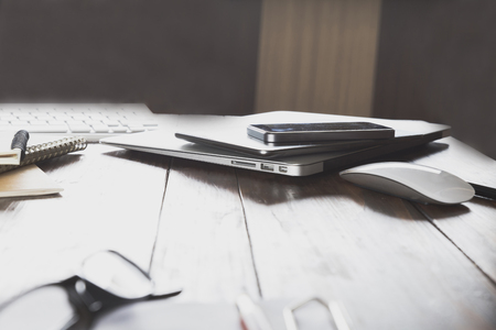 laptop computer, mobile phone and tablet on wooden office deskの写真素材