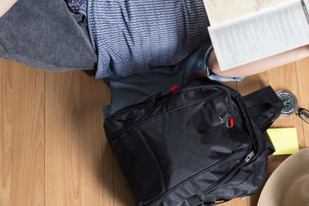 woman lying on wooden floor with map, backpack and compassの写真素材