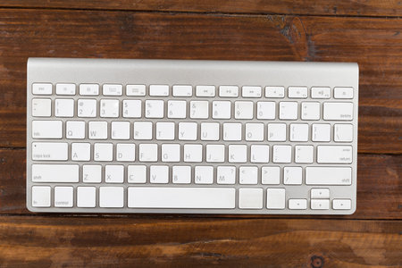 computer keyboard on brown wooden table - top view