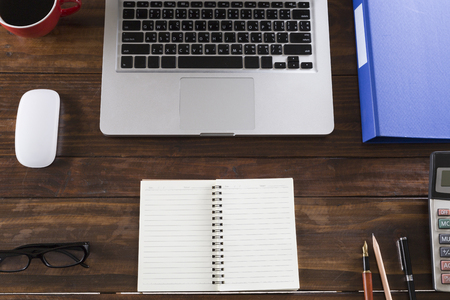 laptop computer and notepad on wooden office desk - top viewの写真素材