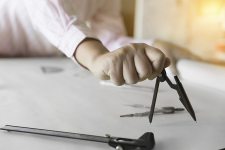 architect hand holding compass working on construction engineering project blueprintの写真素材