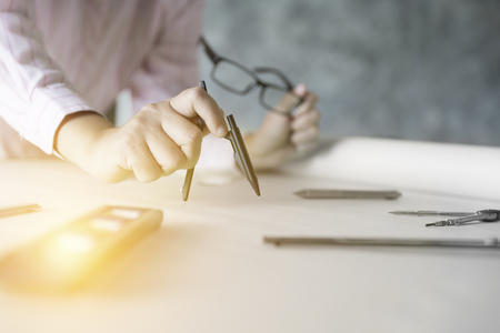 architect hand holding compass working on construction engineering project blueprintの写真素材