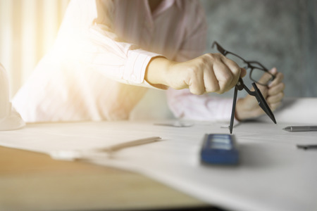 architect hand holding compass working on construction engineering project blueprintの写真素材
