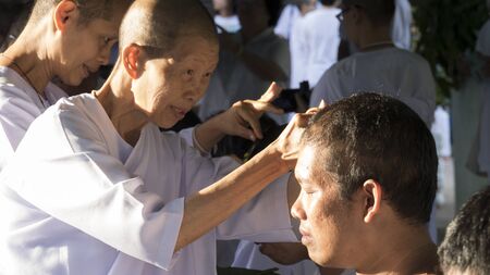 Lampang, Thailand - July 18, 2016: people cut hair of man who will become buddhism monk in ordination ceremony at Bunyanupab temple in Lampang, Thailand on July 18, 2016.のeditorial素材