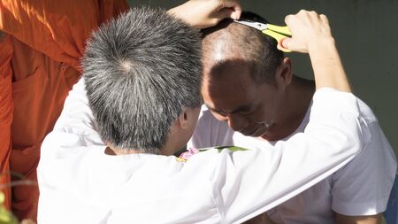 Lampang, Thailand - July 18, 2016: people cut hair of man who will become buddhism monk in ordination ceremony at Bunyanupab temple in Lampang, Thailand on July 18, 2016.のeditorial素材