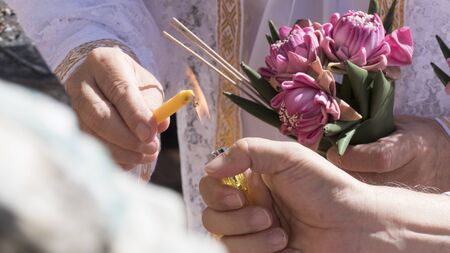 people holding pink lotus and lighting candle in buddhism monk ordination ceremonyの写真素材